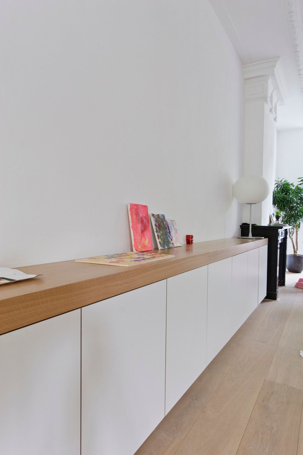 Lang wit dressoir met eiken blad vol kunstwerkjes en een lamp.