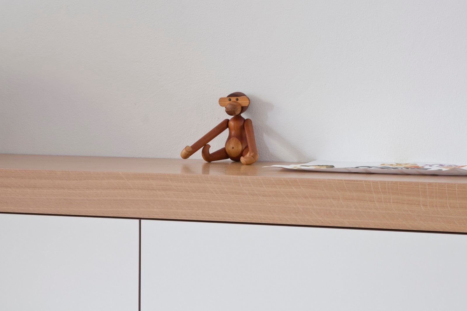 Houten aapfiguurtje op de rand van het eiken blad.