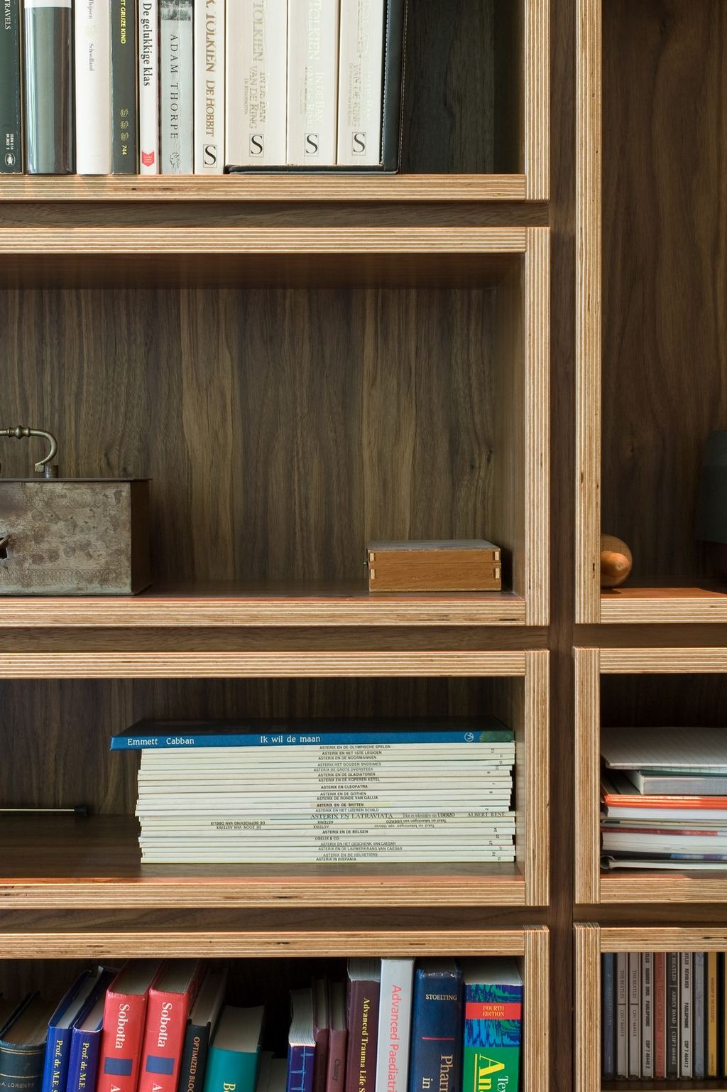 Notenfineer boekenkast met lege vakken en een houten kistje.