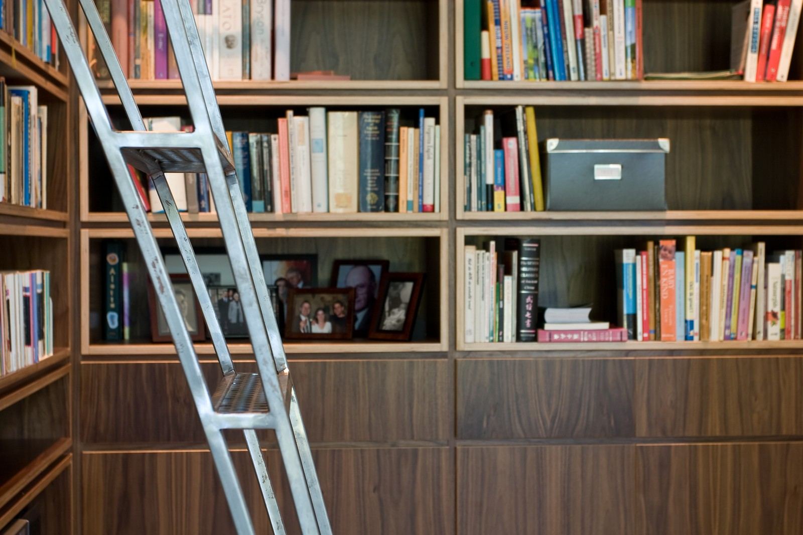 Stalen rolladder voor een notenfineer boekenkast met fotolijstjes.