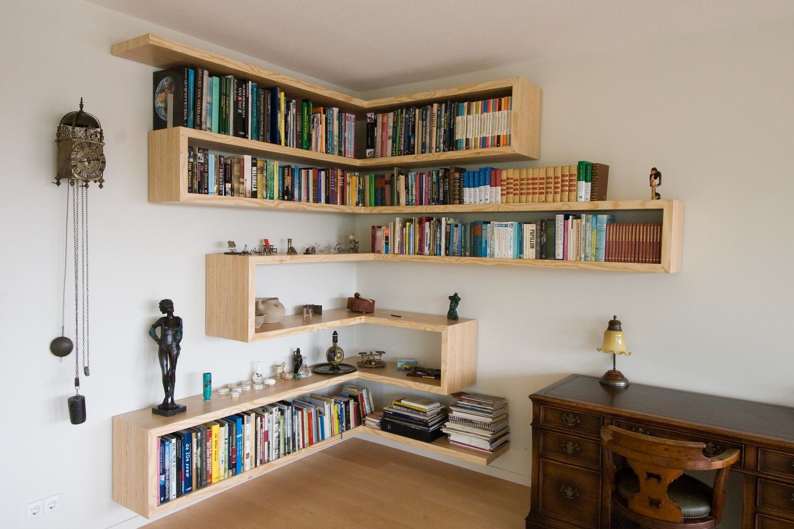 Zwevende plexwood boekenplanken die om de hoek van de kamer slingeren.