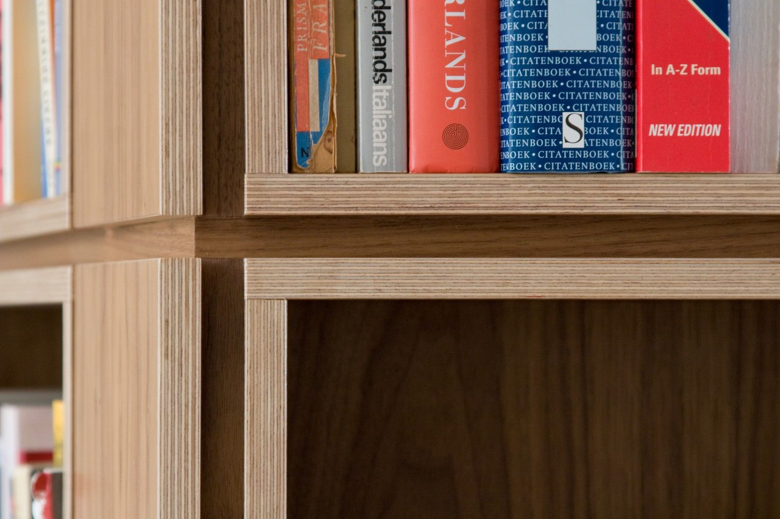 Detail van de open kruising tussen boekenkastvakken, met beeldjes op de bovenste planken.