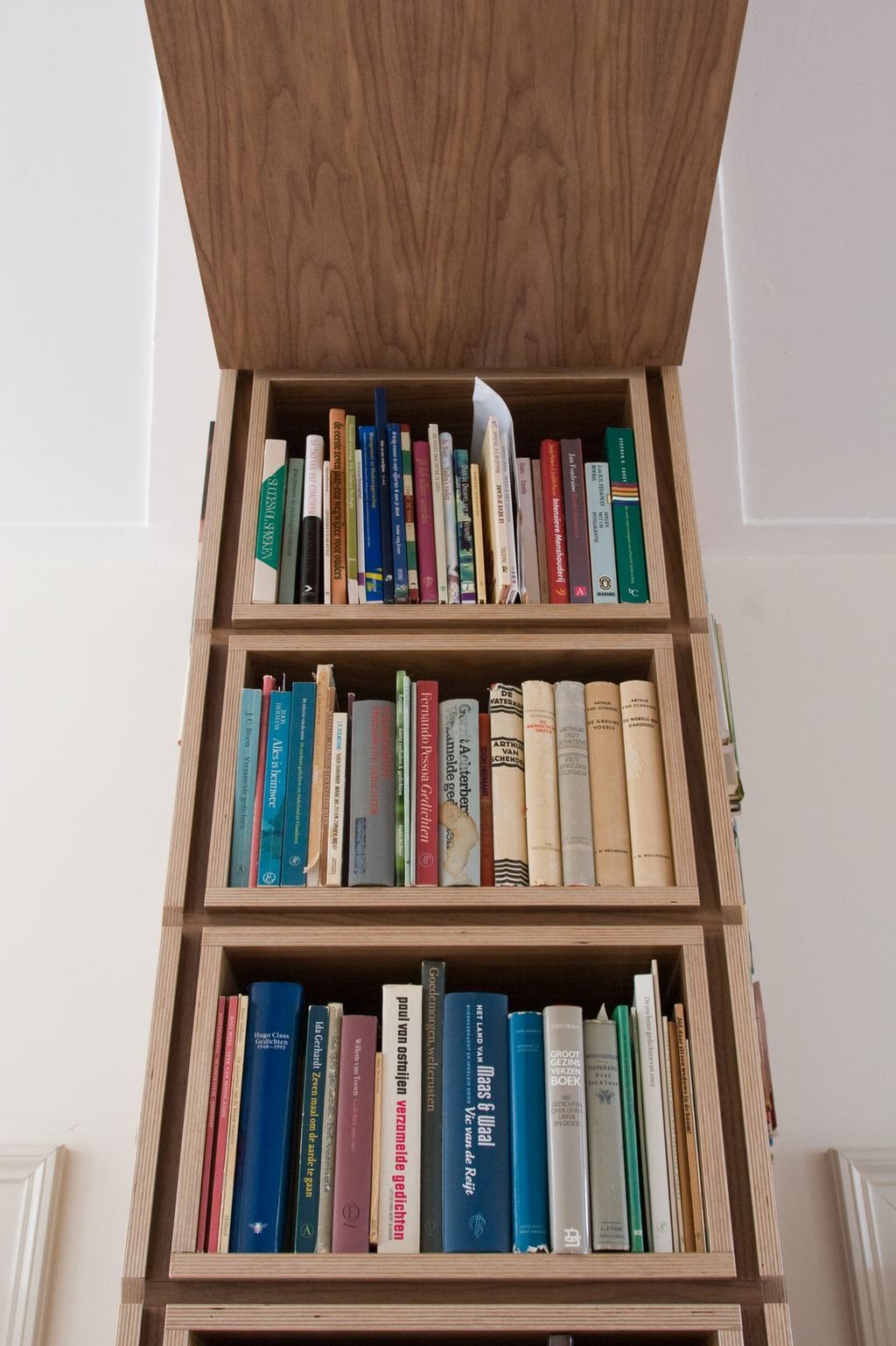 Hoge boekenkastkolom met een klapdeur die de bovenkant afsluit.