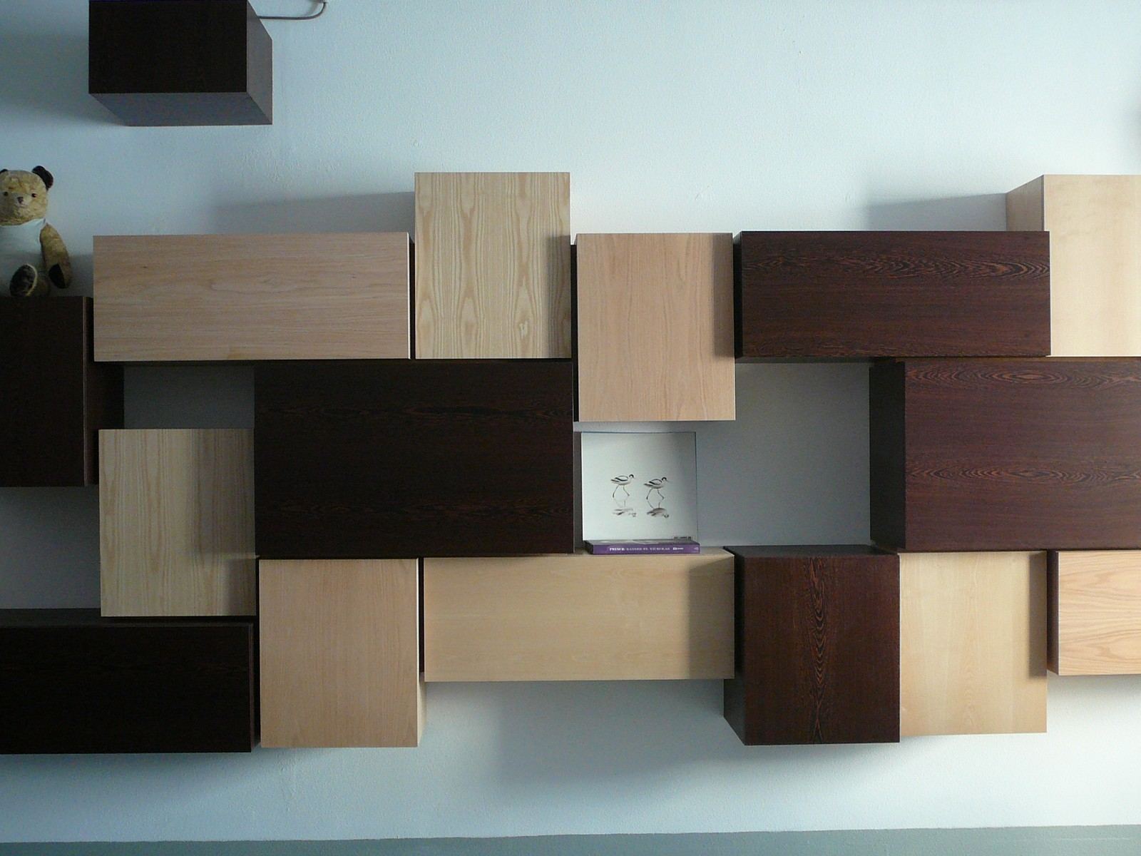 Wandmeubel met stapeling van volumes in wengé, essen en berken multiplex.