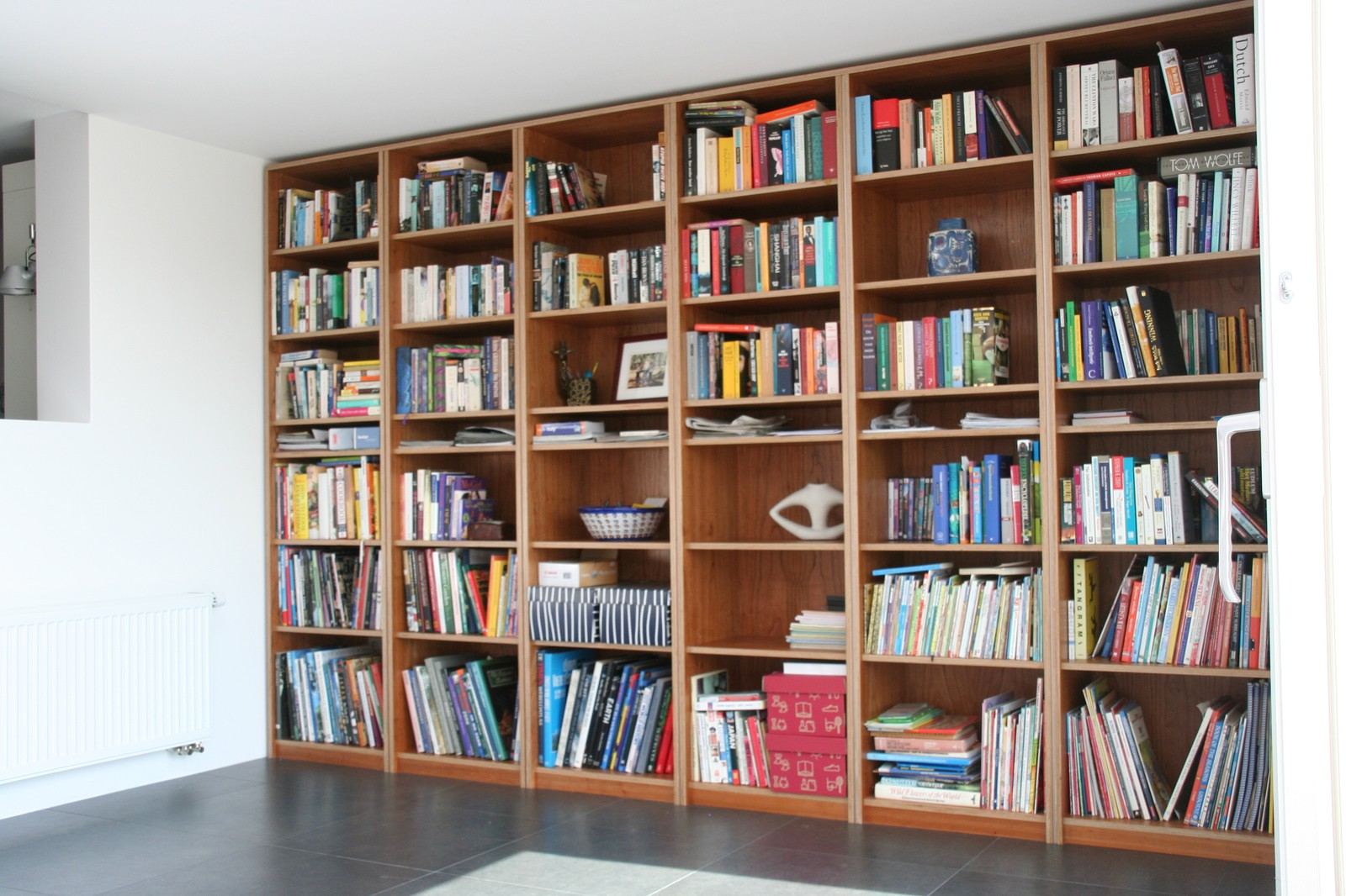 Kamerbrede boekenkast van kersen fineer met verticale vakindeling.