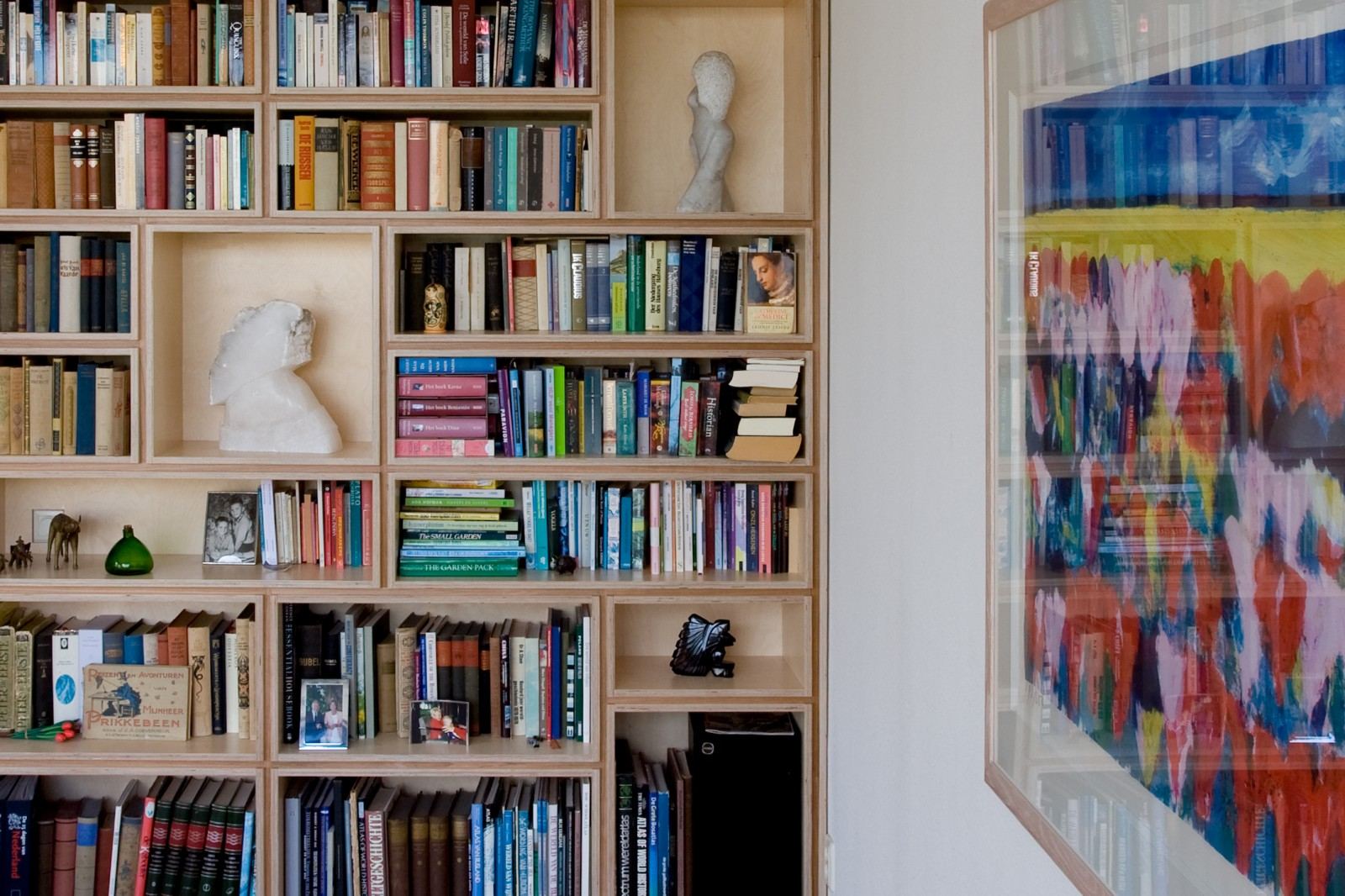 Detail van vakken met boeken en stenen beeldjes in de kast.