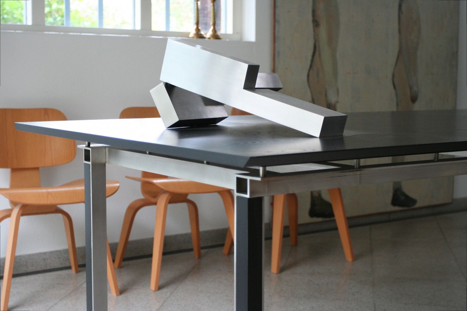 Eettafel met zwart essen fineer blad op een stalen onderstel.