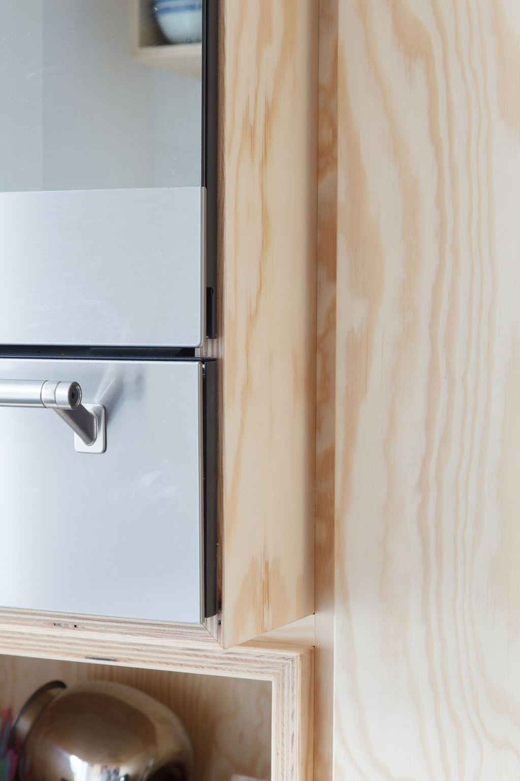 Detail van de multiplex rand naast de ingebouwde oven.