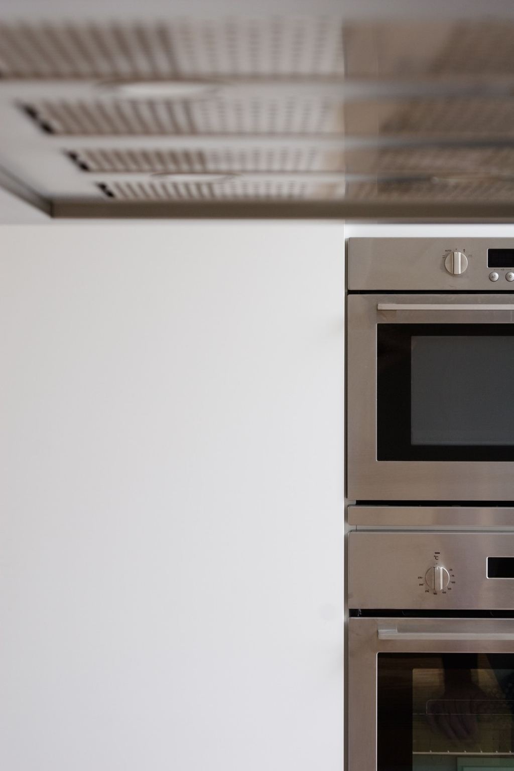 Detail van de afzuigkap en oven naast het witte kastfront.