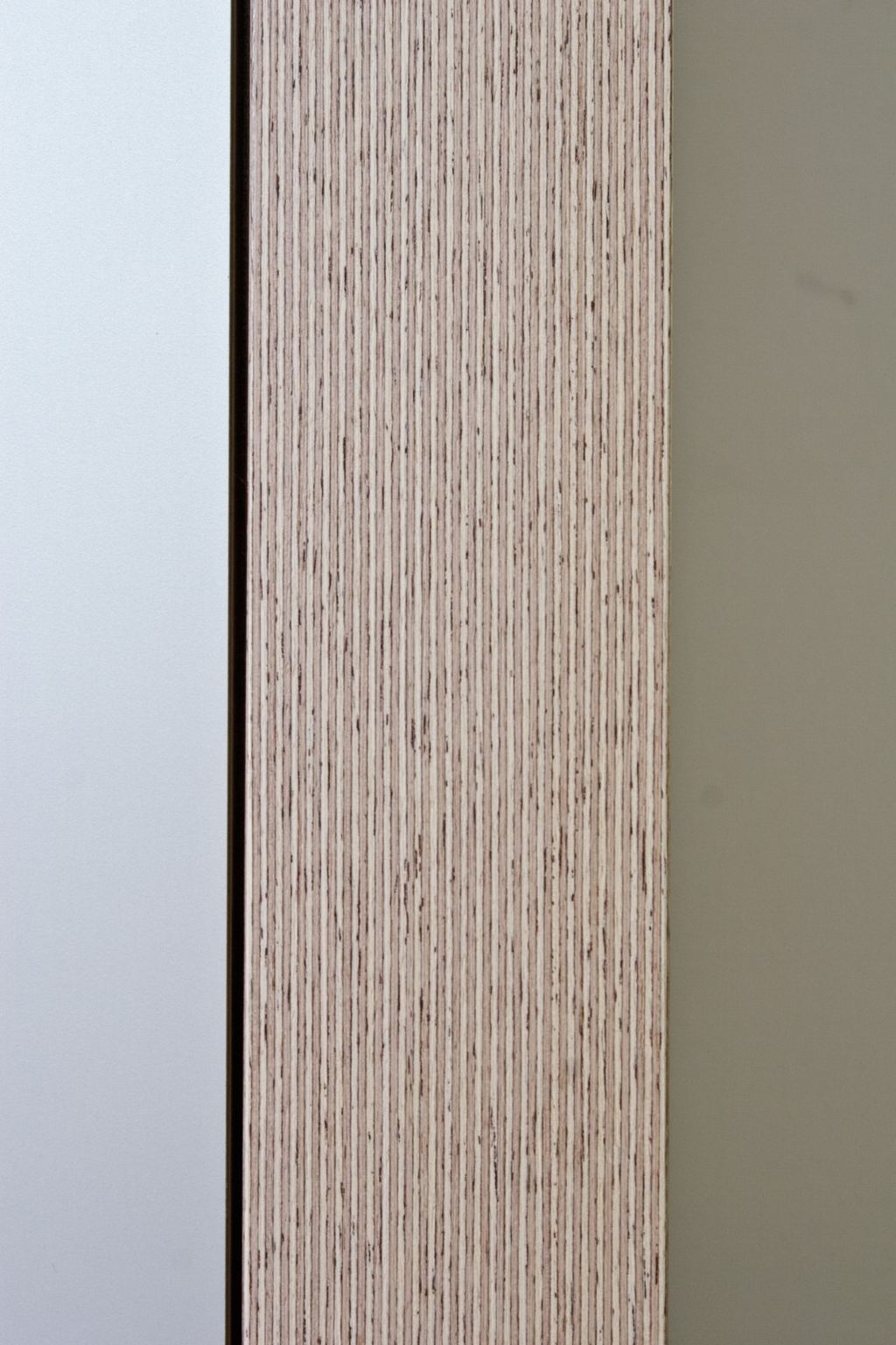 Close-up van de kantano fineer nerf naast witte kastdeuren.