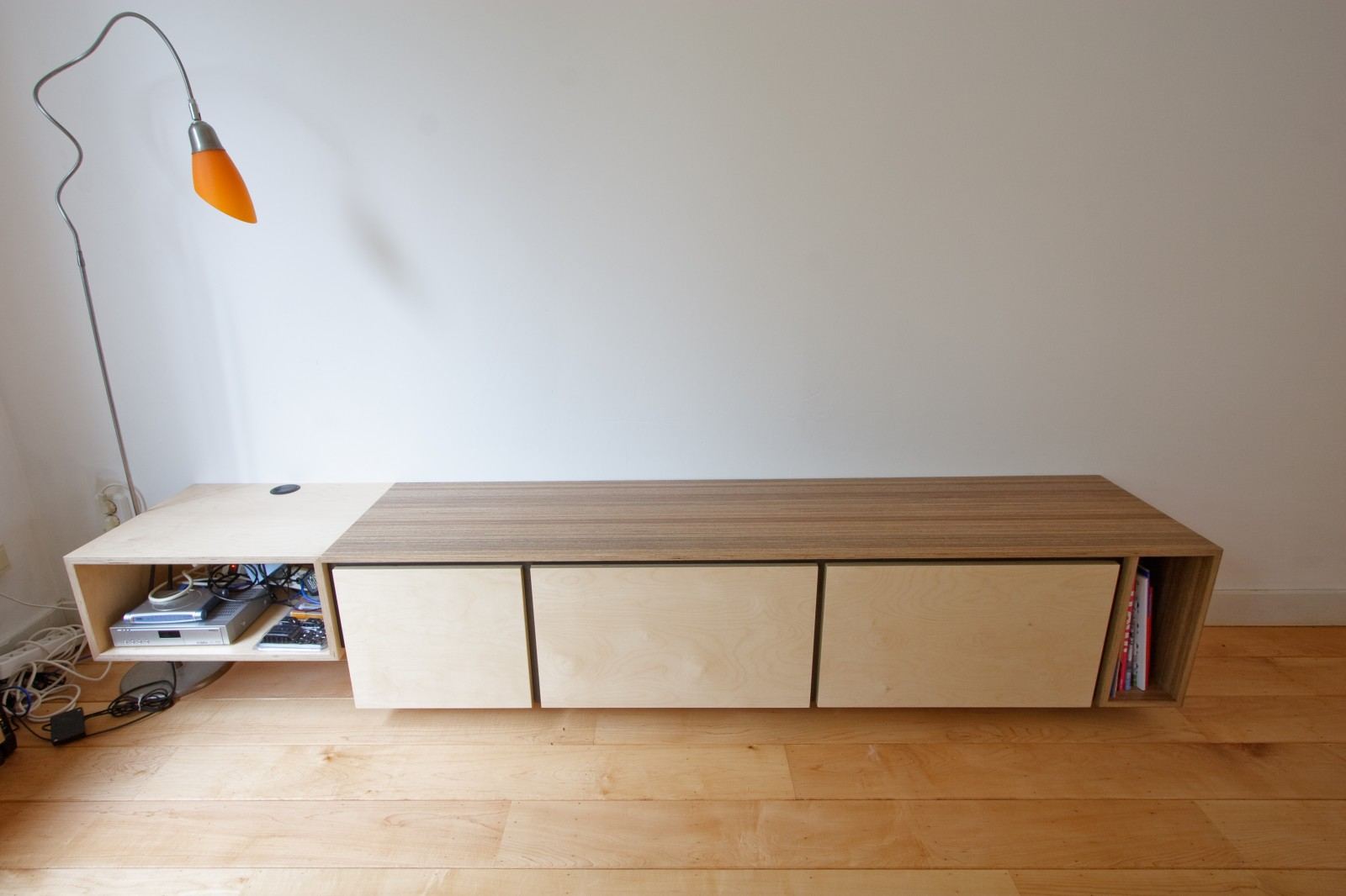 Zwevend tv-meubel met een open vak voor apparatuur en een gestreepte houten looprand op het blad.