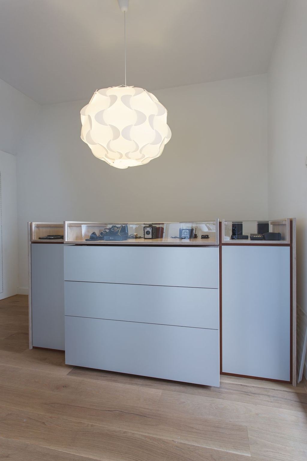 Lage kastenserie met glazen vitrines vol vintage telefoons en camera's.