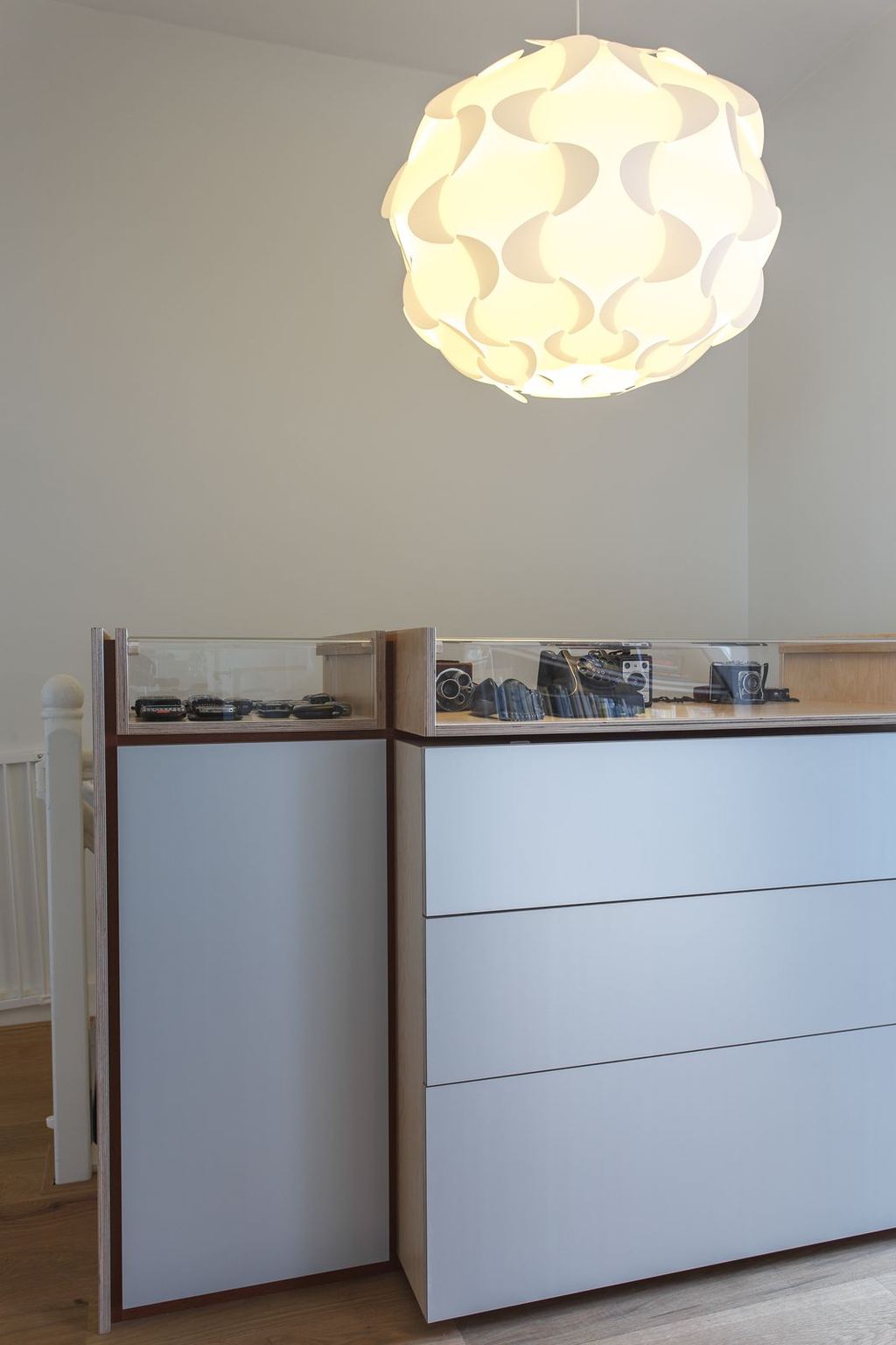 Kastenserie met een vitrine vol camera's en telefoons boven aluminium fronts.