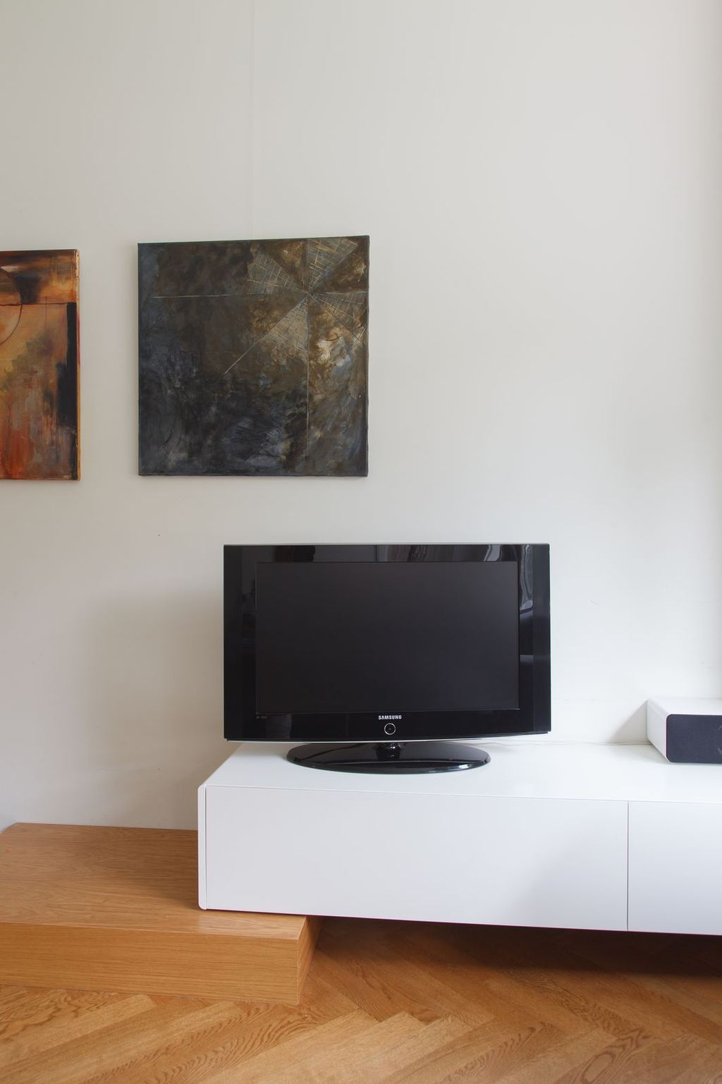 Zwevend wit dressoir met televisie op een eiken plint.