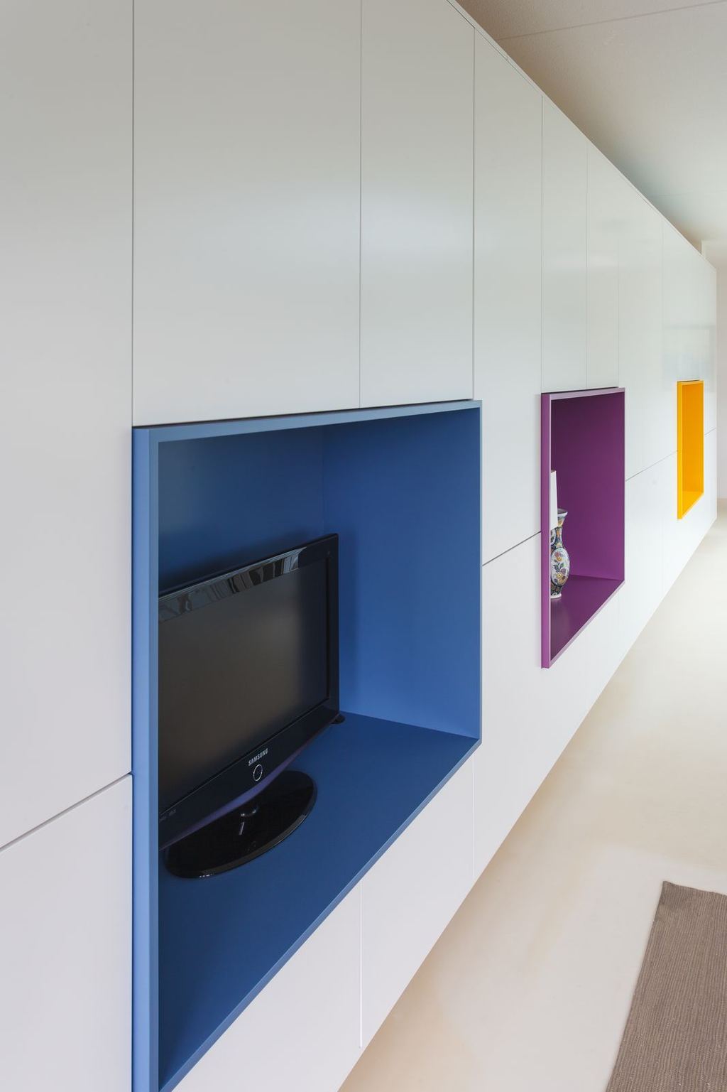 Blauwe en paarse kastopeningen met een televisie en een vaas.