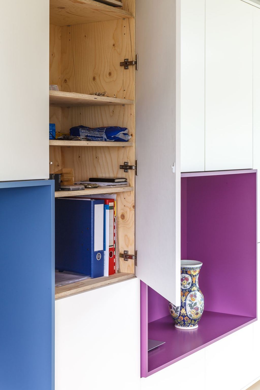 Open kastdeur onthult een interieur van vuren multiplex met ordners.