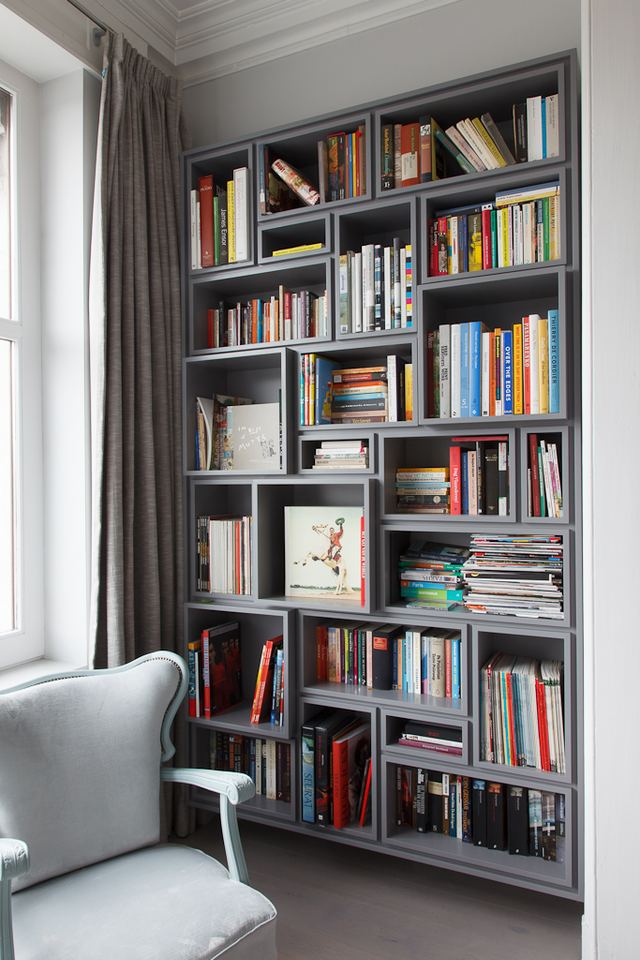 Grijze boekenkast met een raster van vakken in wisselende diepte.