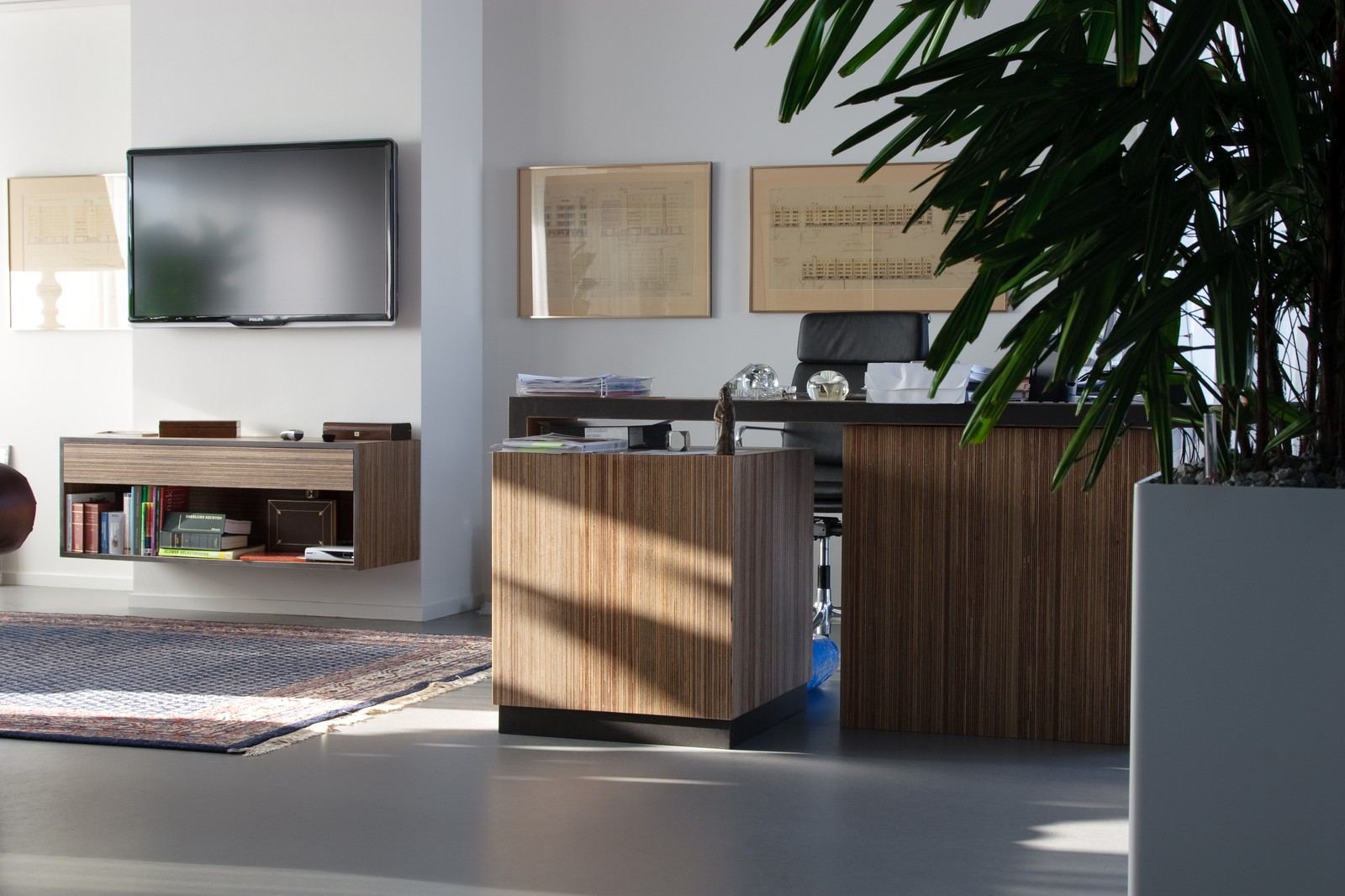 Zwevende kast met boekenvak naast een bureau met zebrano onderstel.