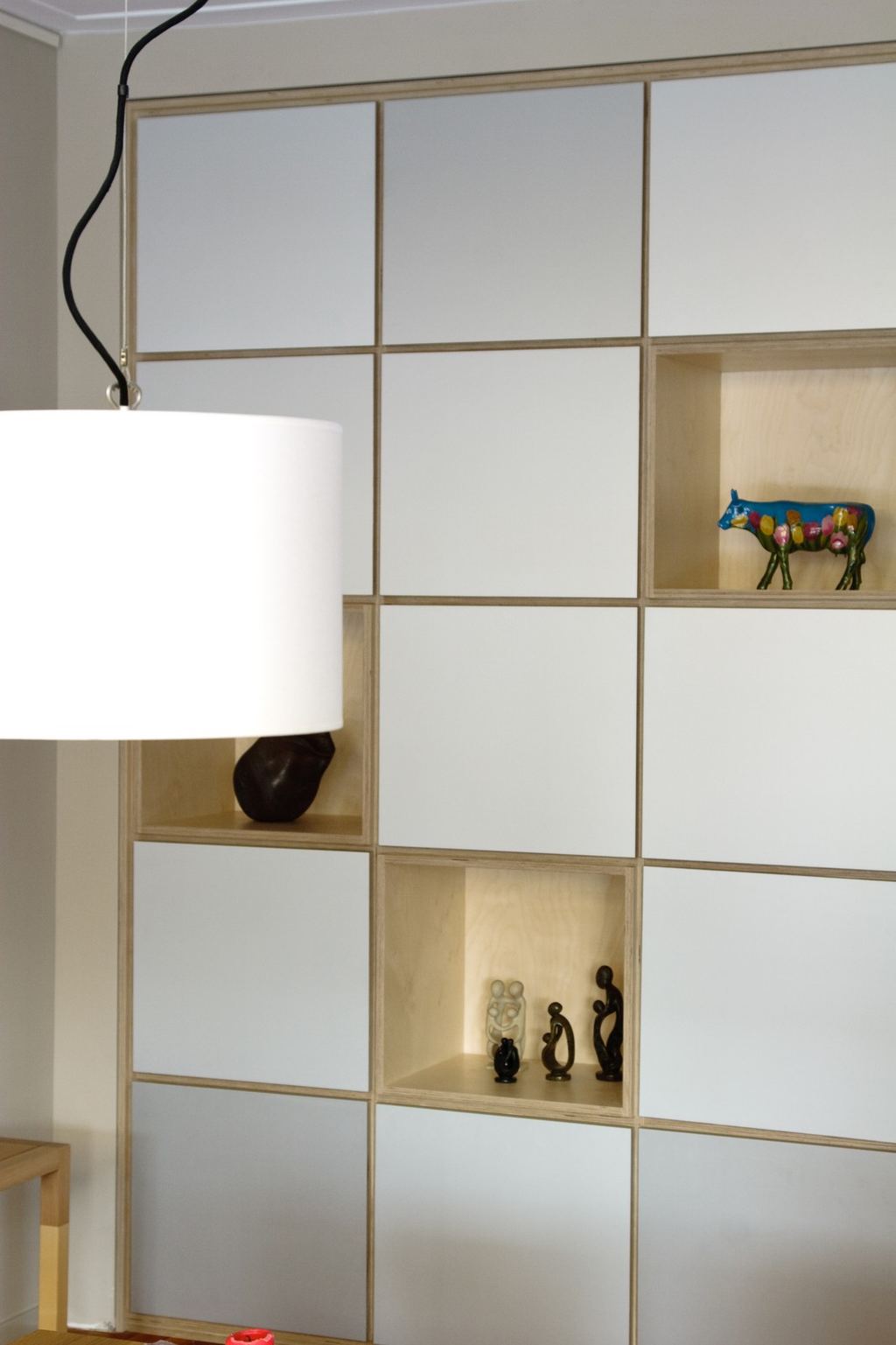 Detail van de kast met open vakjes en een gekleurd koebeeldje.