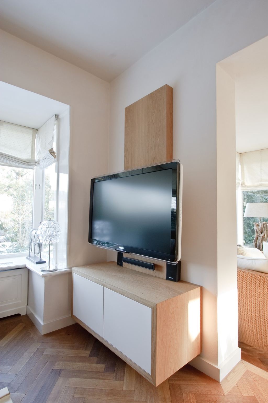 Zwevend tv-meubel met witte kastdeuren, met een televisie op een zwevend paneel erboven.
