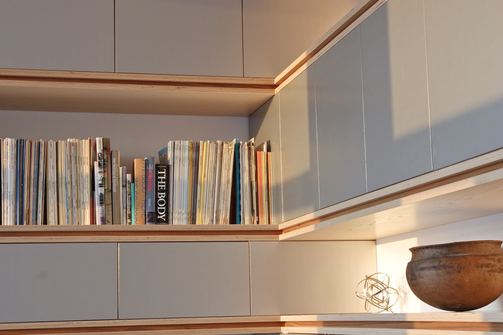 Hoek van de kast met tijdschriften en een aardewerken kom.