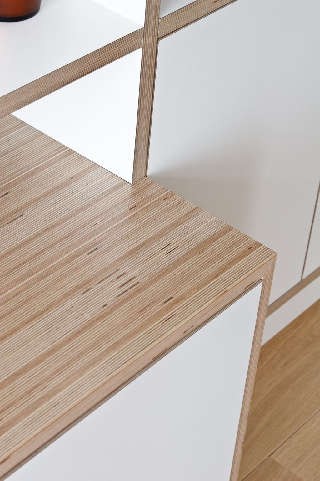 Detail van de gestreepte multiplex rand naast witte kastdeuren.
