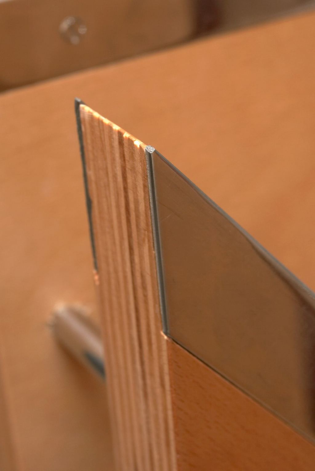 Detail van de beuken multiplex laagjes naast de stalen rand.