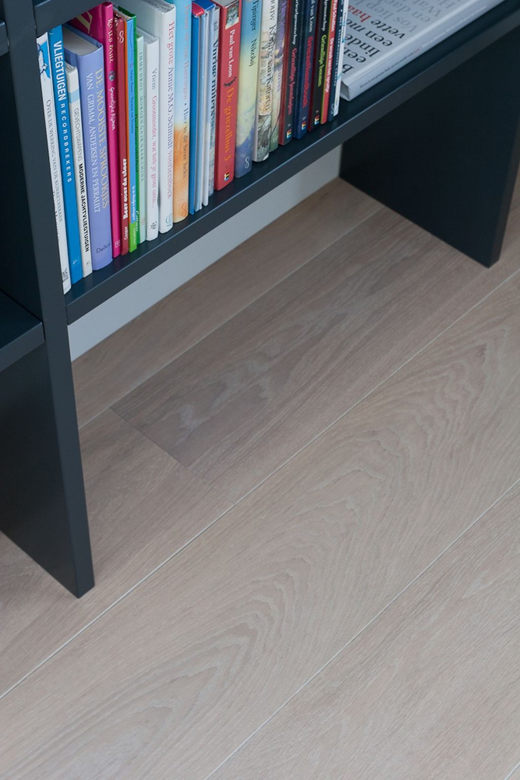 Onderste vak van de zwarte boekenkast, met kinderboeken erin.