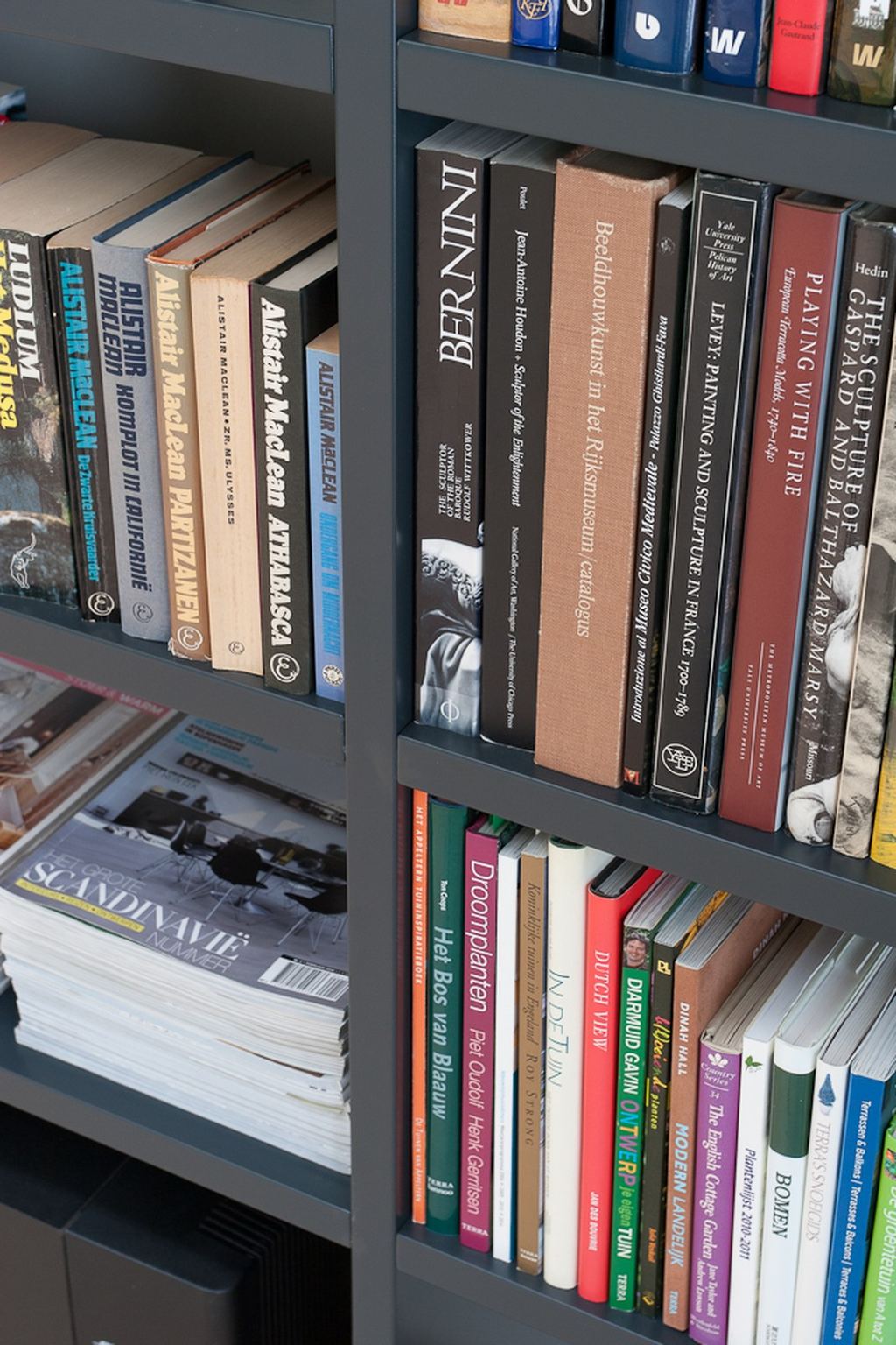 Zwarte boekenkast schuin in beeld, gevuld met kunstboeken.
