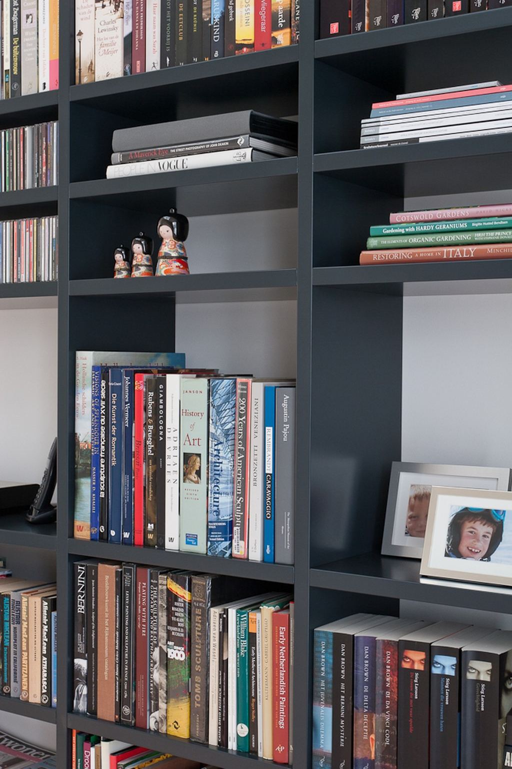 Detail van de zwarte boekenkast met fotolijstjes en beeldjes.