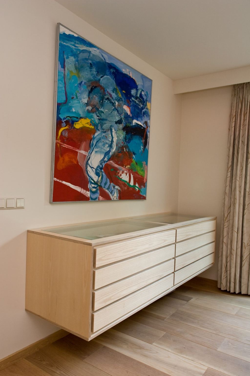 Zwevend dressoir met een glazen vitrinedeksel boven acht laden met een ingefreesde grip.