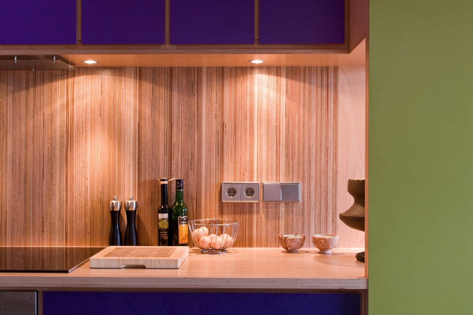 Werkblad met olie-, peper- en zoutmolens naast een groene wand.
