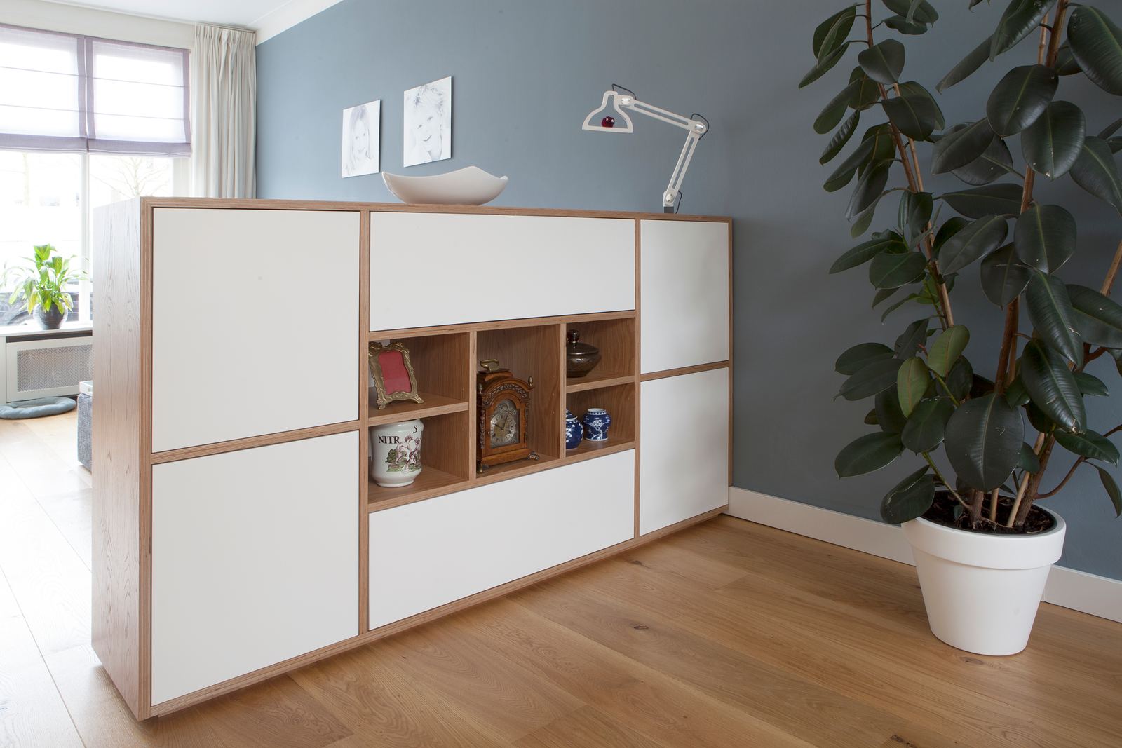 Lage room divider met witte kastdeuren en een open vak met snuisterijen.