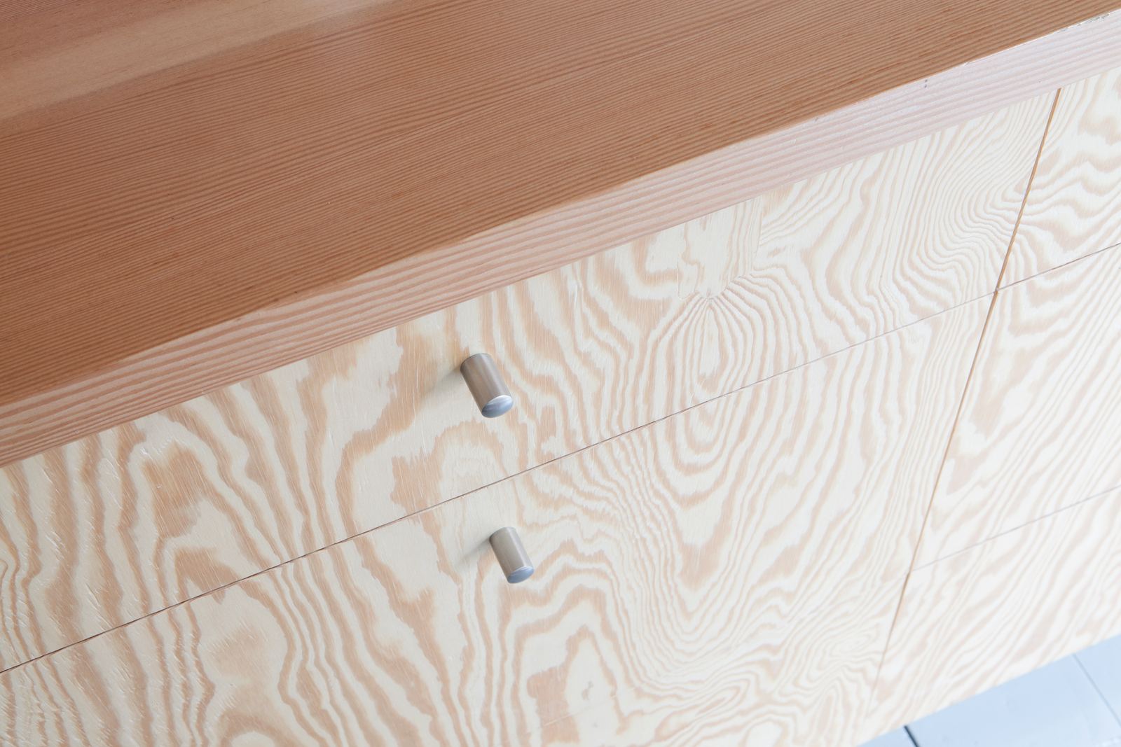 Detail van twee ronde metalen knoppen op houten kastfronten.