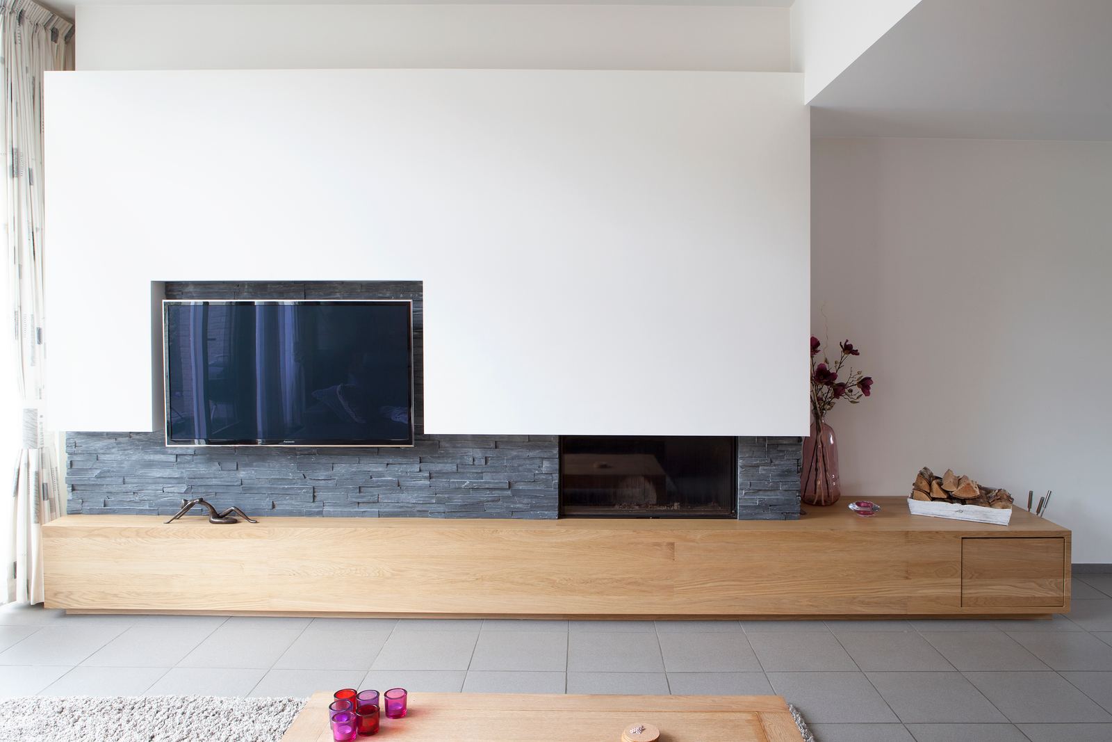 Zwevend eiken kastelement onder een gashaard, met een verhoogde TV-nis.