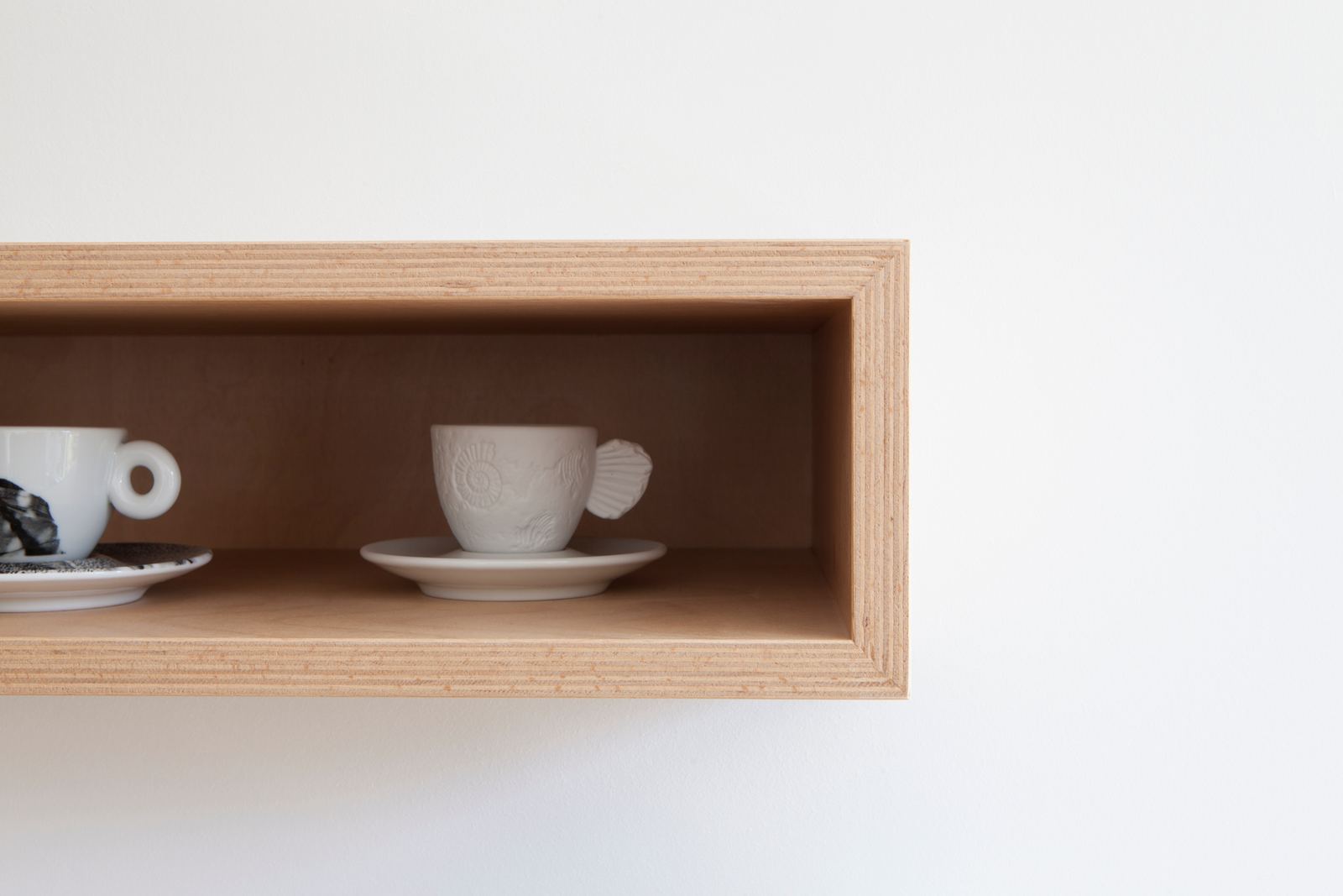 Diepe berken multiplex box met een espressokopje op schotel.
